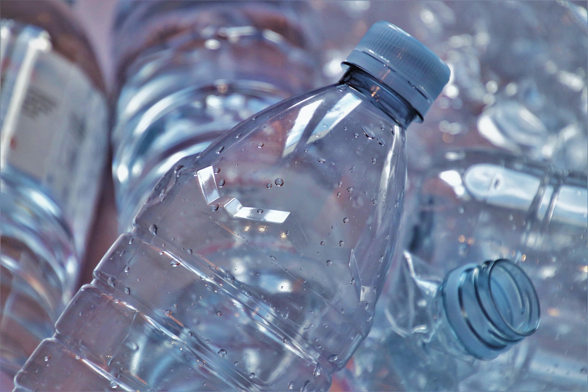 Nahaufnahme mehrerer transparenter Plastikflaschen mit Wassertropfen, die dicht beieinander liegen und das Thema Kunststoffrecycling verdeutlichen.